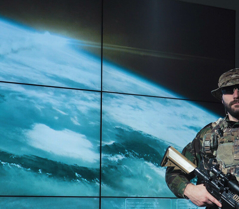 Two soldiers standing in front of a screen showing the world