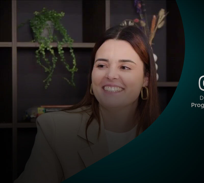 Vrouw glimlacht tijdens gesprek in een modern interieur met wandplanken en planten.