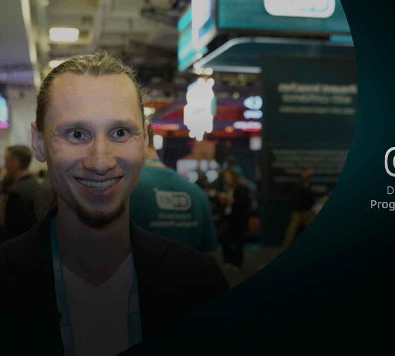 Juraj Janosik glimlacht voor de ESET-stand op RSA Conference 2025, omringd door bezoekers.