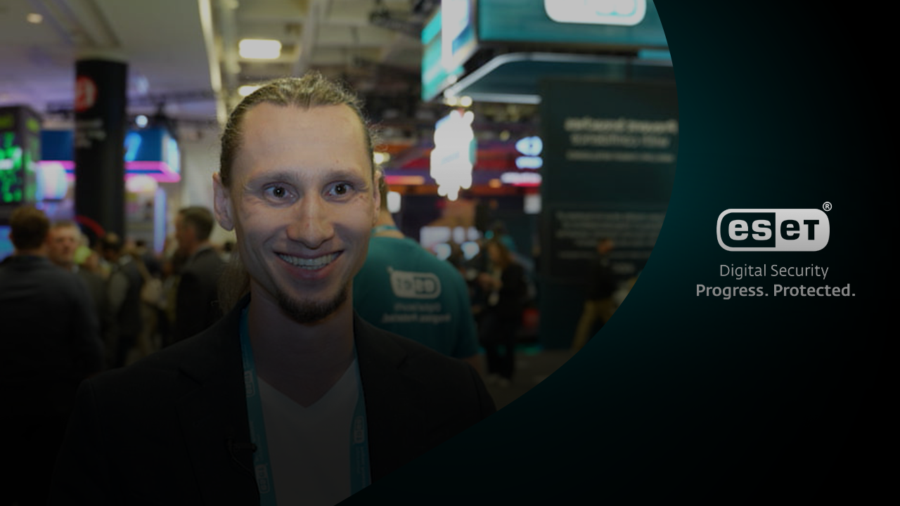 Juraj Janosik glimlacht voor de ESET-stand op RSA Conference 2025, omringd door bezoekers.